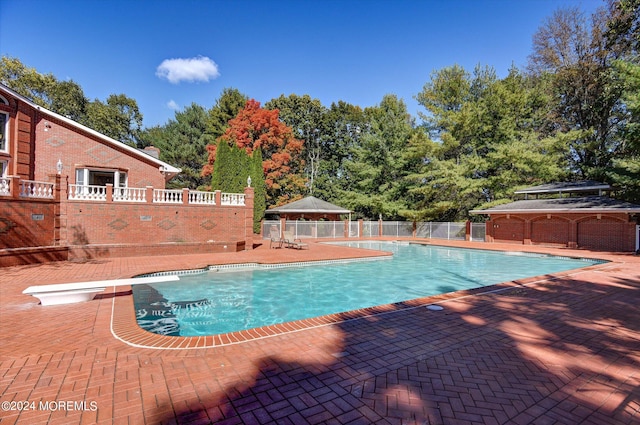 view of swimming pool with a patio area and a diving board