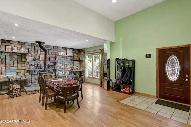 dining space with light hardwood / wood-style flooring, a textured ceiling, and a wood stove