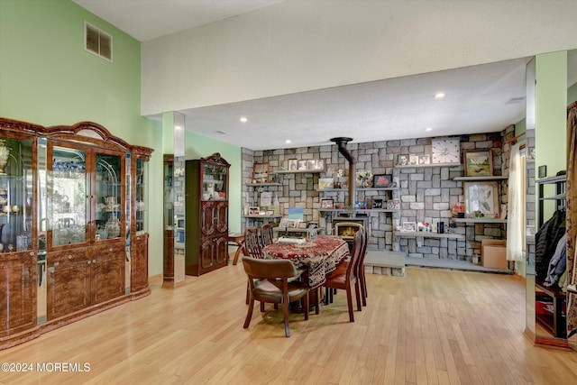 dining room with light hardwood / wood-style flooring, a wood stove, and a high ceiling