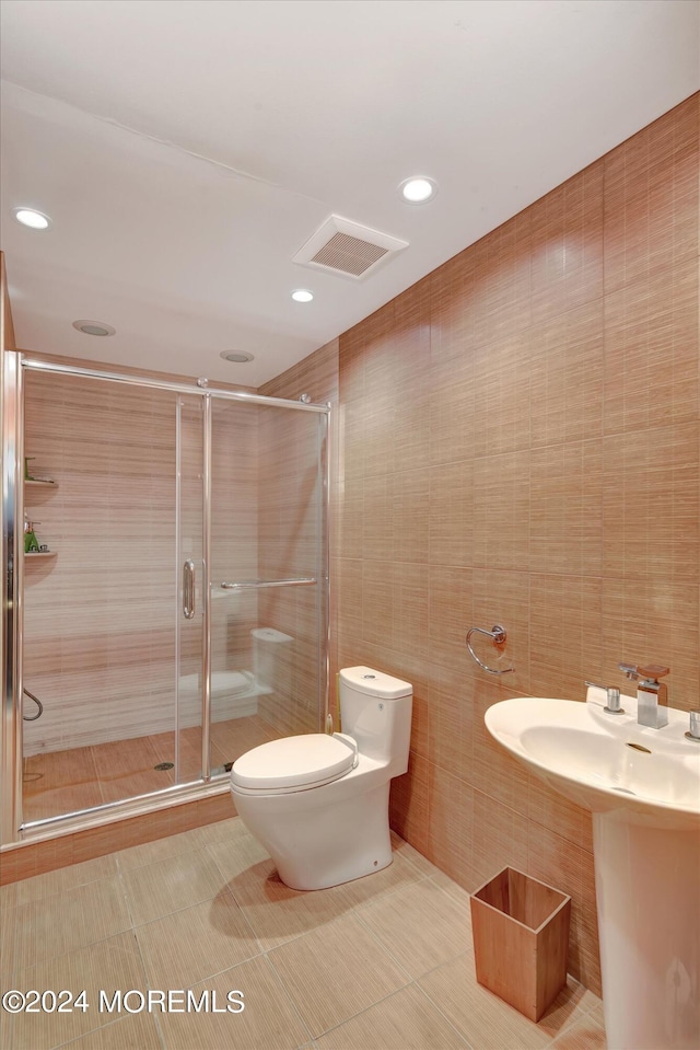 bathroom with toilet, tile walls, and an enclosed shower