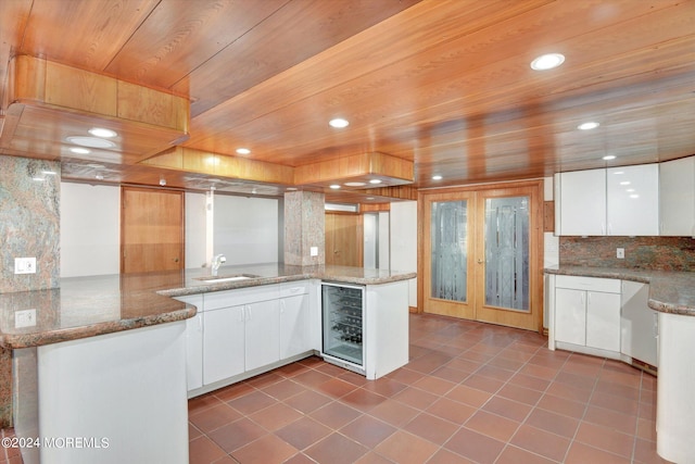 kitchen featuring white cabinetry, wine cooler, stone counters, and kitchen peninsula