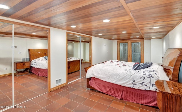 tiled bedroom featuring wood ceiling and two closets