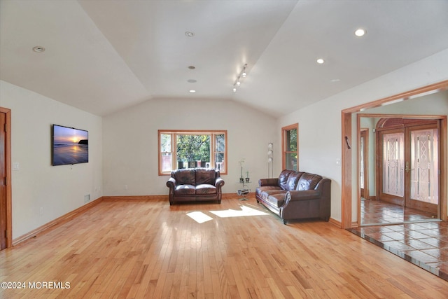 unfurnished living room with french doors, light hardwood / wood-style floors, and vaulted ceiling