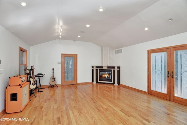 living room featuring french doors, lofted ceiling, and light wood-type flooring