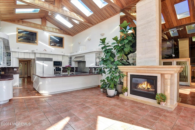 kitchen featuring appliances with stainless steel finishes, light tile patterned flooring, high vaulted ceiling, and white cabinets