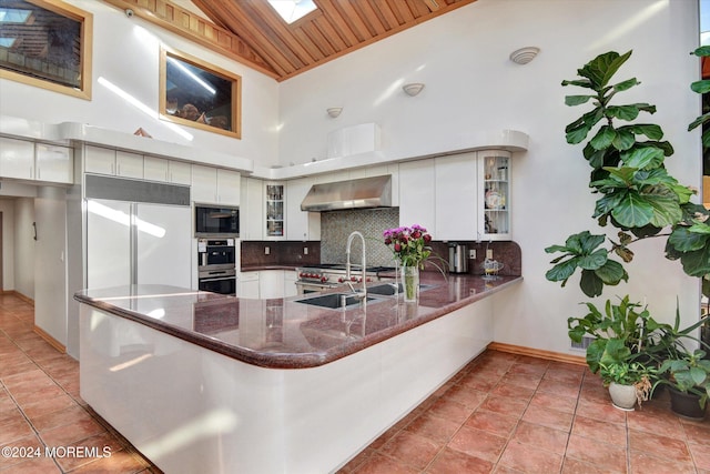 kitchen featuring appliances with stainless steel finishes, white cabinetry, wall chimney range hood, and wooden ceiling