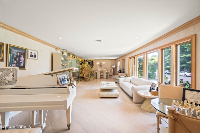 living room with crown molding, light hardwood / wood-style flooring, and a chandelier