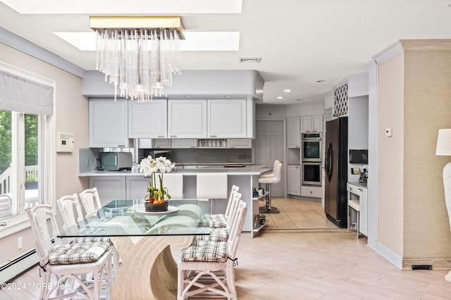 kitchen with pendant lighting, appliances with stainless steel finishes, a skylight, and light wood-type flooring