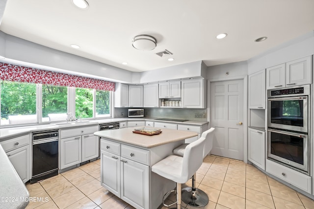 kitchen with appliances with stainless steel finishes, white cabinets, sink, and a kitchen island