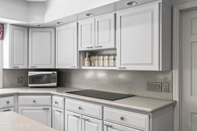 kitchen with ornamental molding, black electric cooktop, white cabinetry, and tasteful backsplash