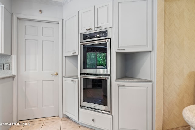 kitchen featuring ornamental molding, white cabinets, double oven, and light tile patterned floors