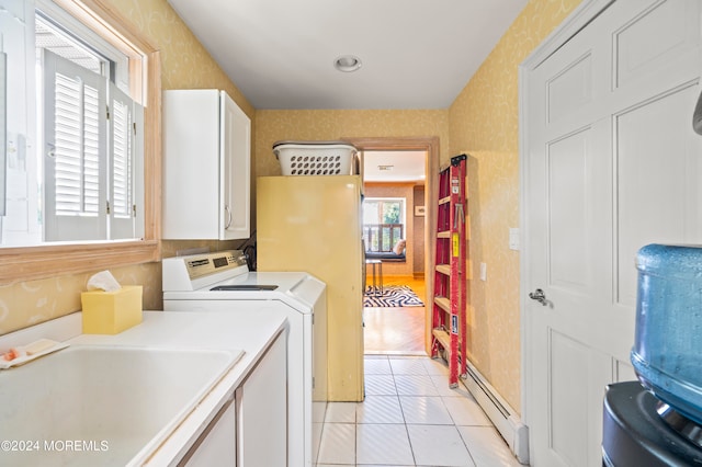 washroom featuring a baseboard heating unit, independent washer and dryer, sink, light tile patterned floors, and cabinets