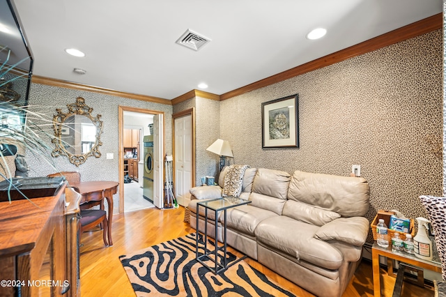 living room featuring light hardwood / wood-style floors, ornamental molding, and washer / dryer