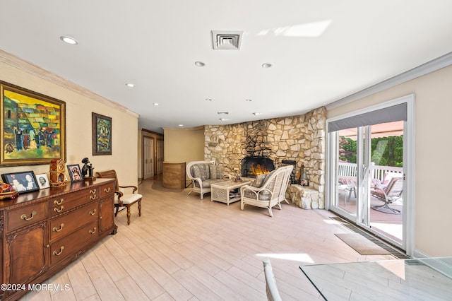 living area with ornamental molding, a fireplace, and light wood-type flooring