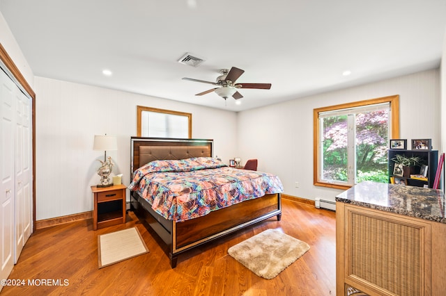 bedroom featuring a closet, ceiling fan, hardwood / wood-style flooring, and a baseboard radiator