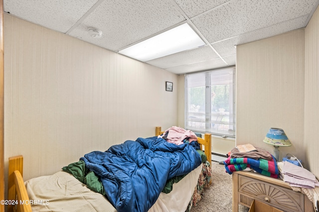 carpeted bedroom featuring a baseboard radiator and a drop ceiling