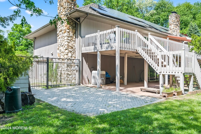 rear view of house featuring a wooden deck, a patio area, and a yard