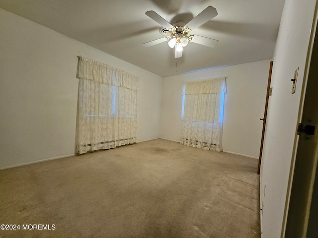 carpeted spare room with a baseboard heating unit and ceiling fan