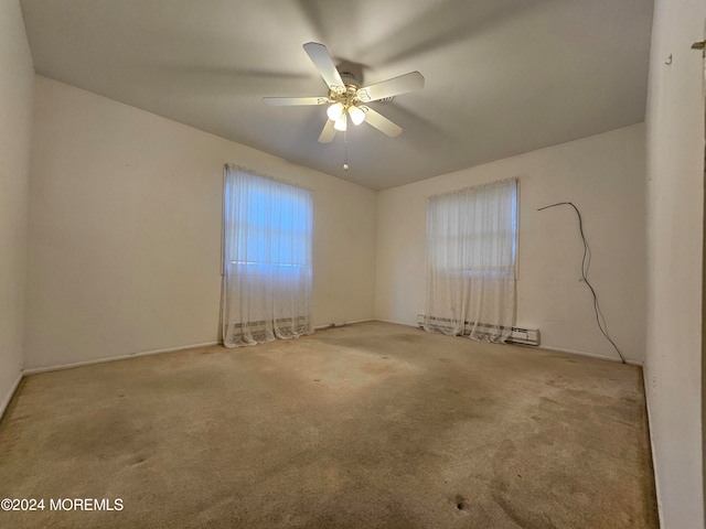 carpeted spare room featuring ceiling fan, a baseboard radiator, and a wealth of natural light