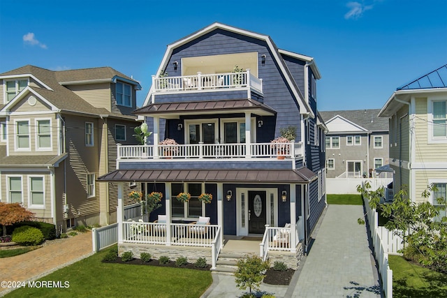 view of front of property featuring covered porch, a balcony, and a front lawn