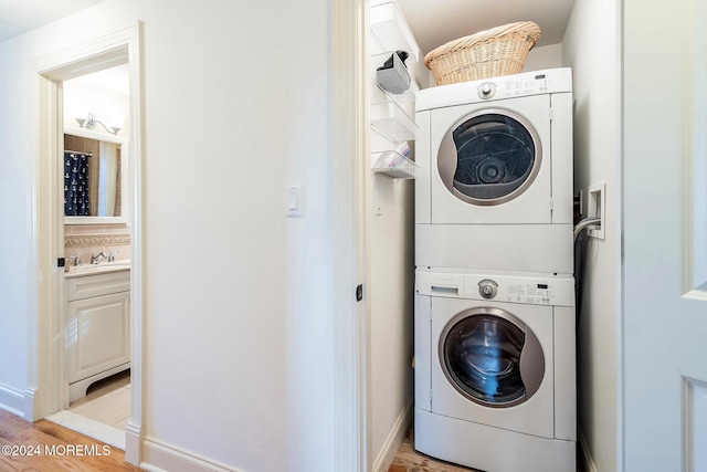 laundry area with stacked washing maching and dryer and light wood-type flooring