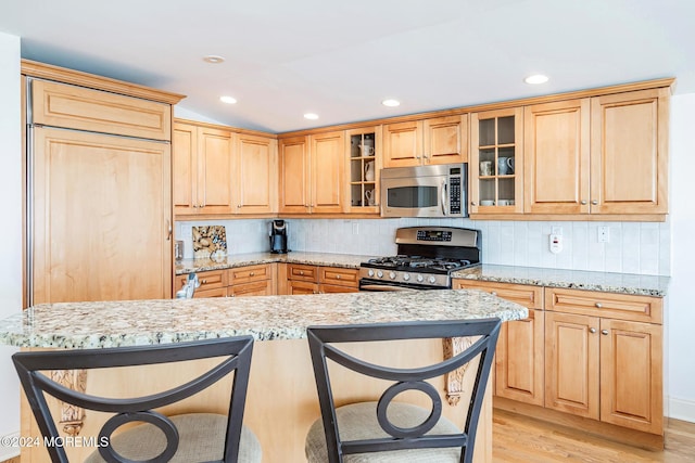 kitchen featuring light stone countertops, light hardwood / wood-style flooring, stainless steel appliances, and tasteful backsplash