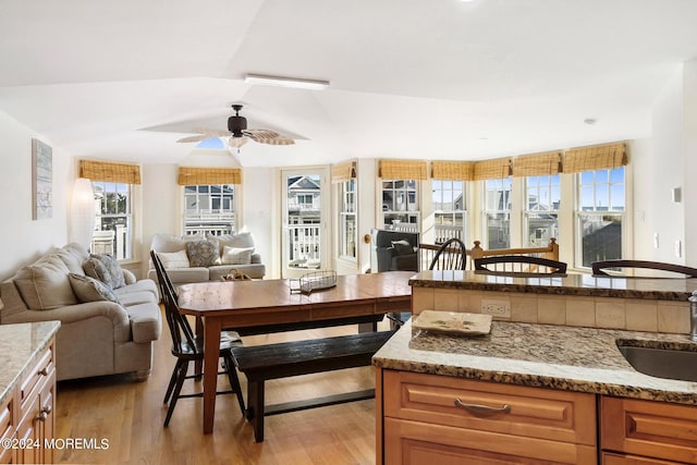 kitchen featuring light stone countertops, sink, ceiling fan, vaulted ceiling, and light hardwood / wood-style flooring