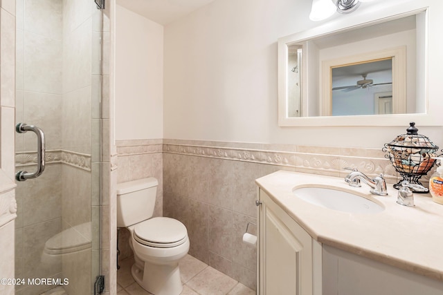 bathroom featuring a shower with shower door, toilet, tile walls, vanity, and tile patterned flooring