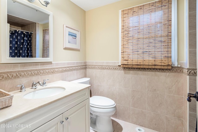 bathroom featuring vanity, toilet, and tile walls