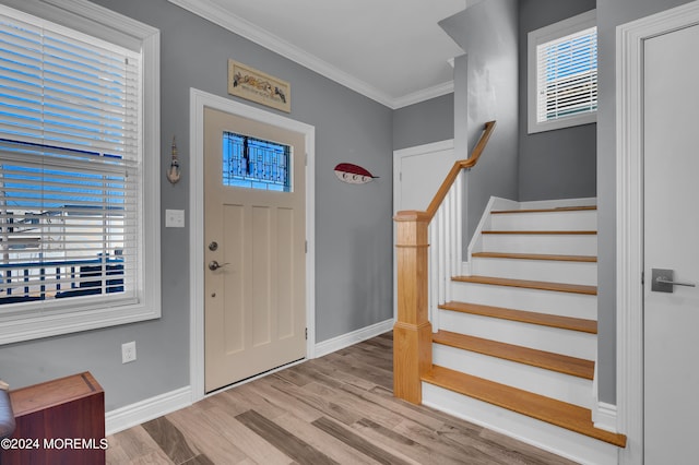 entryway with a wealth of natural light, crown molding, and light wood-type flooring