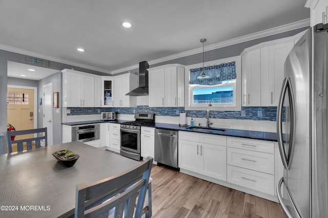 kitchen with sink, light wood-type flooring, hanging light fixtures, stainless steel appliances, and wall chimney exhaust hood