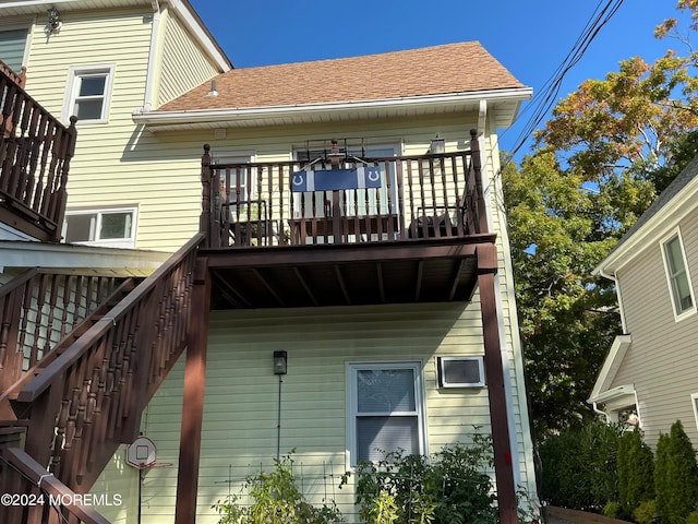 back of house featuring stairway and a shingled roof