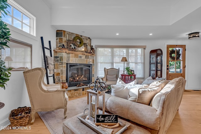 living room with a stone fireplace and light wood-type flooring