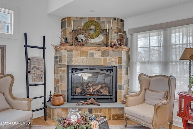 sitting room featuring wood-type flooring, a stone fireplace, and crown molding