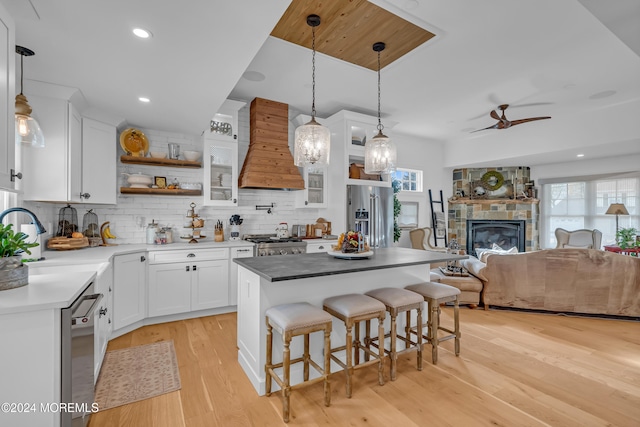 kitchen featuring stainless steel appliances, white cabinetry, custom range hood, a breakfast bar area, and a kitchen island