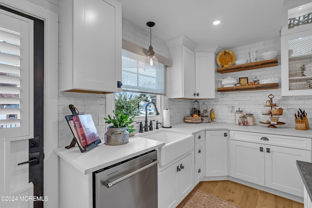 kitchen featuring stainless steel dishwasher, backsplash, white cabinetry, light hardwood / wood-style flooring, and decorative light fixtures