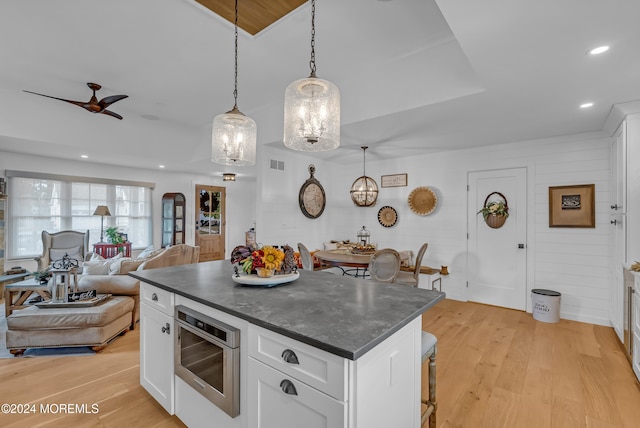 kitchen featuring white cabinetry, decorative light fixtures, and light hardwood / wood-style flooring