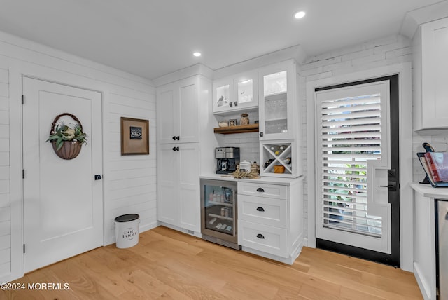 bar featuring beverage cooler, light hardwood / wood-style floors, and white cabinets