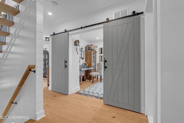 hall featuring hardwood / wood-style floors, a barn door, and ornamental molding