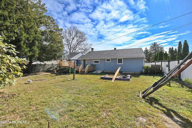 rear view of house with a yard, an outdoor fire pit, and a deck