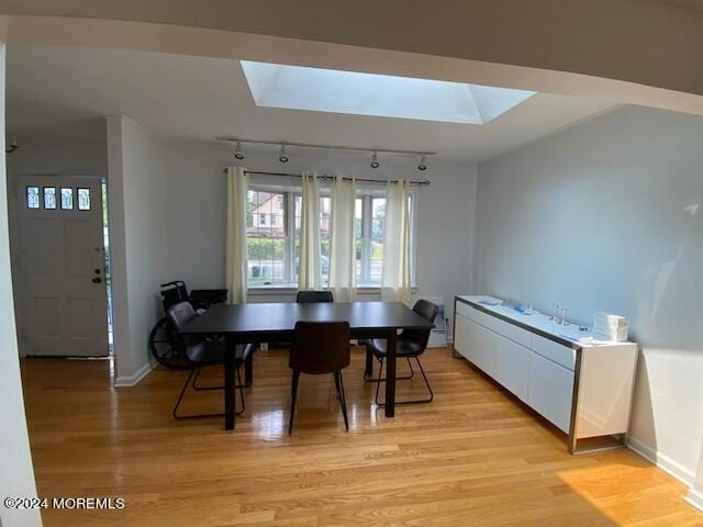 dining space featuring track lighting, light hardwood / wood-style flooring, and a skylight