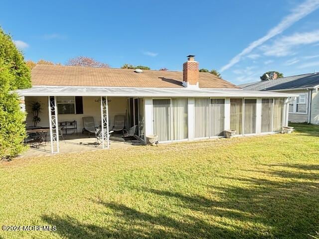 rear view of property with a patio, a chimney, and a yard