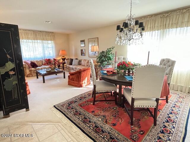 carpeted dining space with visible vents, an inviting chandelier, and tile patterned flooring