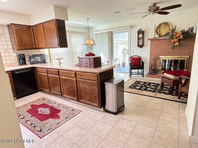 kitchen featuring black appliances, tasteful backsplash, a peninsula, a fireplace, and light countertops