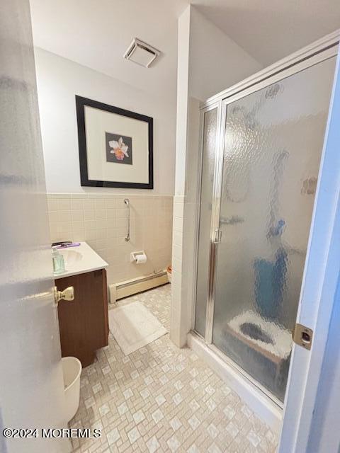 full bath featuring tile walls, visible vents, a shower stall, and a baseboard radiator