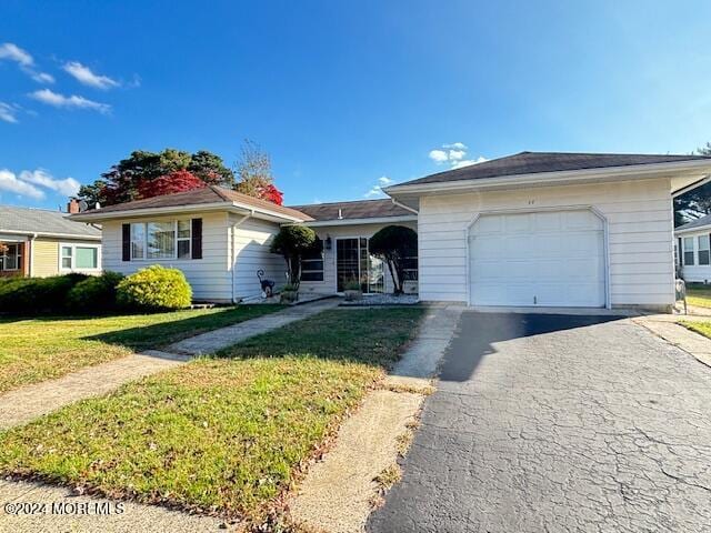 single story home with aphalt driveway, an attached garage, and a front lawn