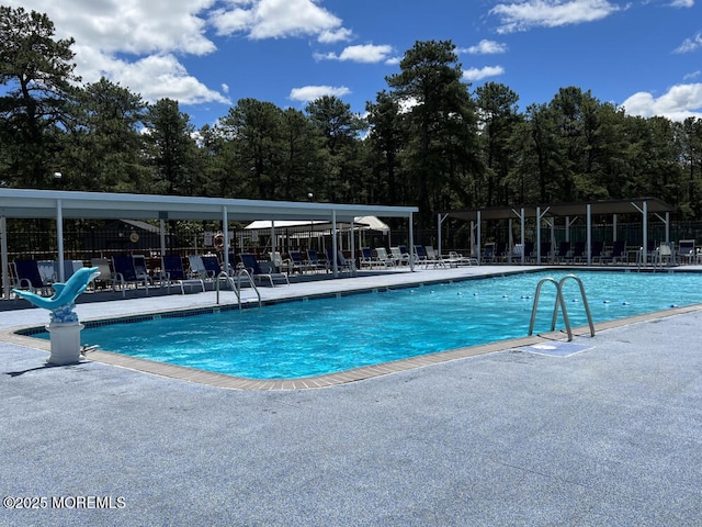 community pool with a patio area and fence