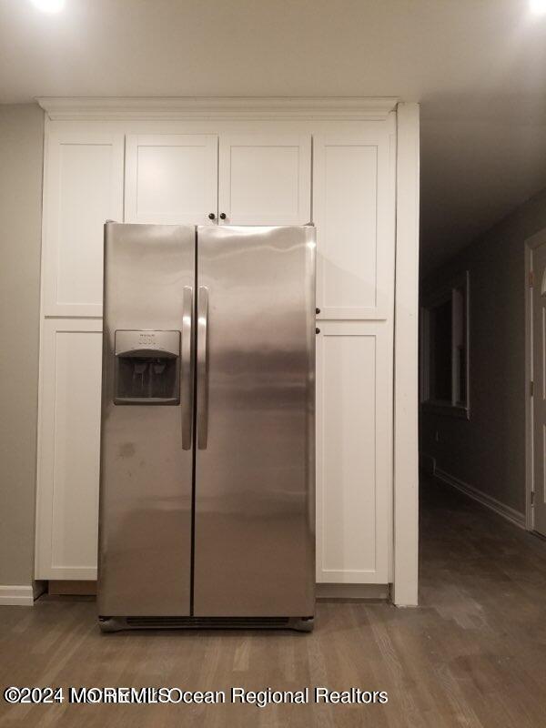 kitchen featuring stainless steel fridge with ice dispenser, hardwood / wood-style flooring, and white cabinetry