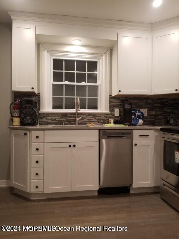 kitchen with appliances with stainless steel finishes, dark hardwood / wood-style floors, and white cabinetry