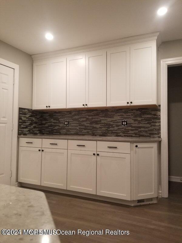 kitchen with white cabinets, backsplash, and dark hardwood / wood-style flooring